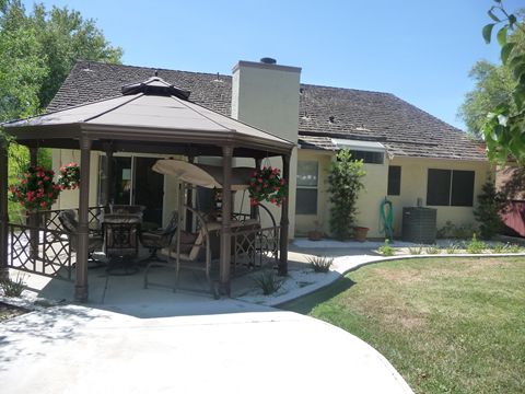 A cozy backyard with a gazebo and patio area, featuring outdoor furniture.