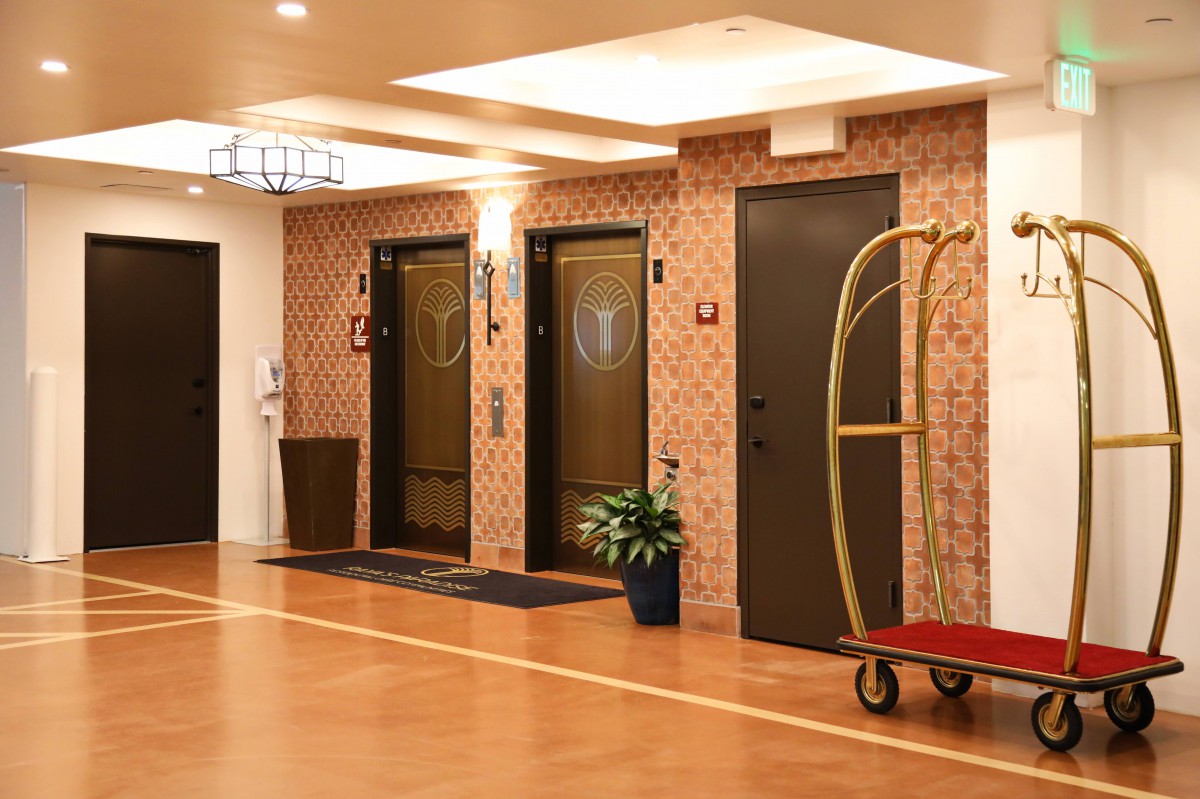 A hotel lobby with elevators and a luggage trolley.