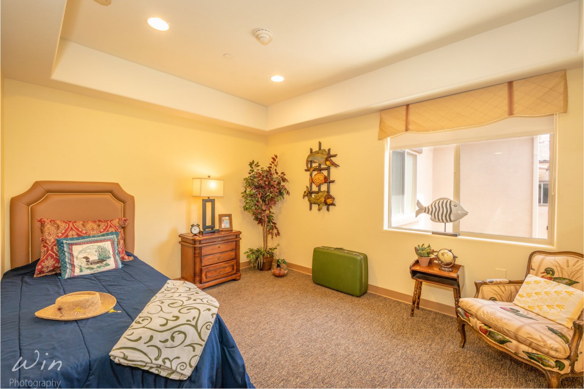 A cozy bedroom with warm lighting, featuring a bed, lamp, and decorative items.
