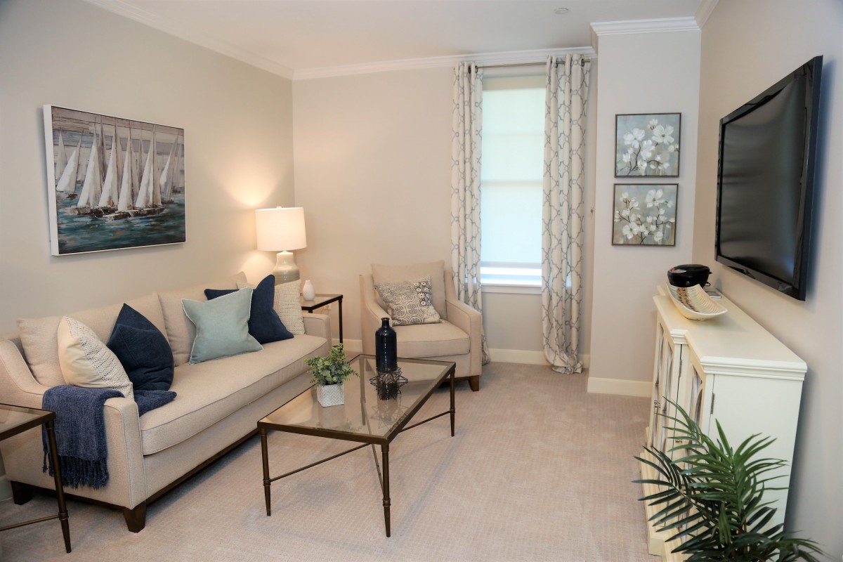 A cozy and elegantly decorated living room featuring a sofa, coffee table, lamp, and wall art.