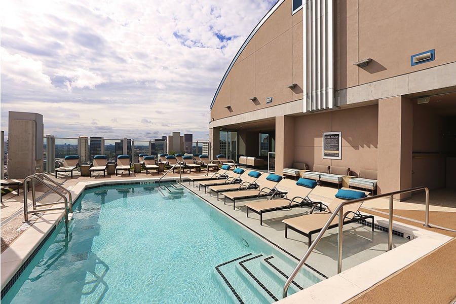 A rooftop pool with lounge chairs overlooking a city skyline.