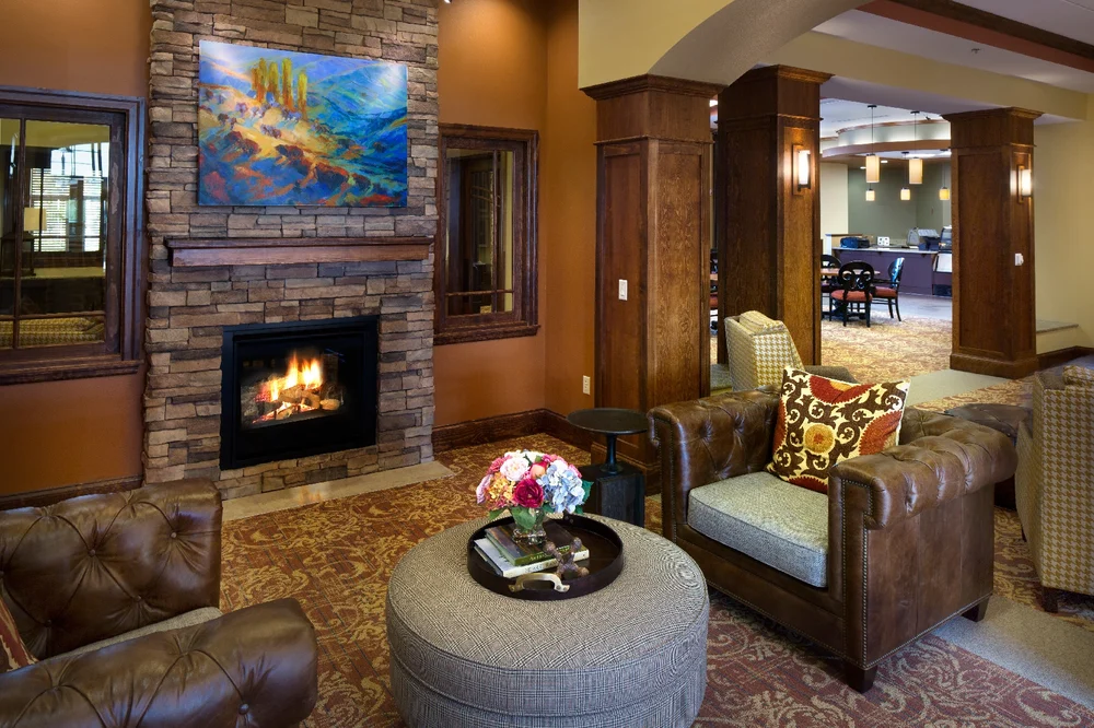 A cozy living room with a brick fireplace, comfortable seating, and decorative artwork.