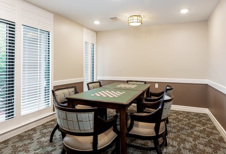 A well-lit dining room with a table and six chairs, featuring large windows and elegant decor.