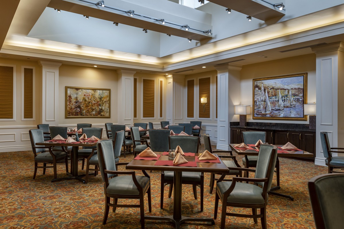 An elegantly set dining room with neatly arranged tables and chairs, surrounded by artwork on the walls.