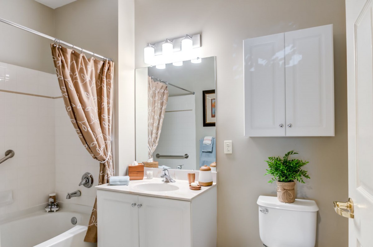 A neatly organized bathroom with a vanity, mirror, and shower area.