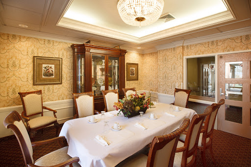 An elegant dining room featuring a beautifully set table, wooden furniture, and an exquisite chandelier.