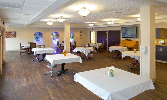 A spacious dining area with neatly arranged tables and chairs, covered with white tablecloths.