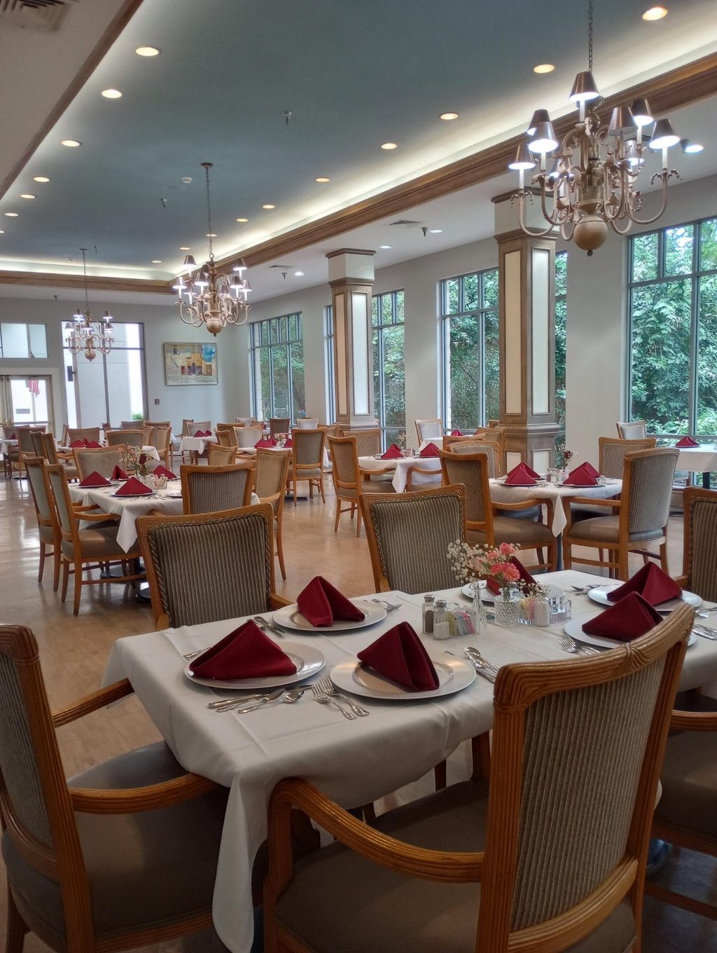 An elegantly set dining room with neatly arranged tables and chandeliers.