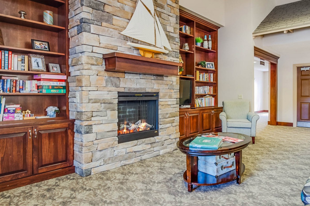 A cozy living room featuring a stone fireplace, wooden bookshelves, and a sailboat decoration.