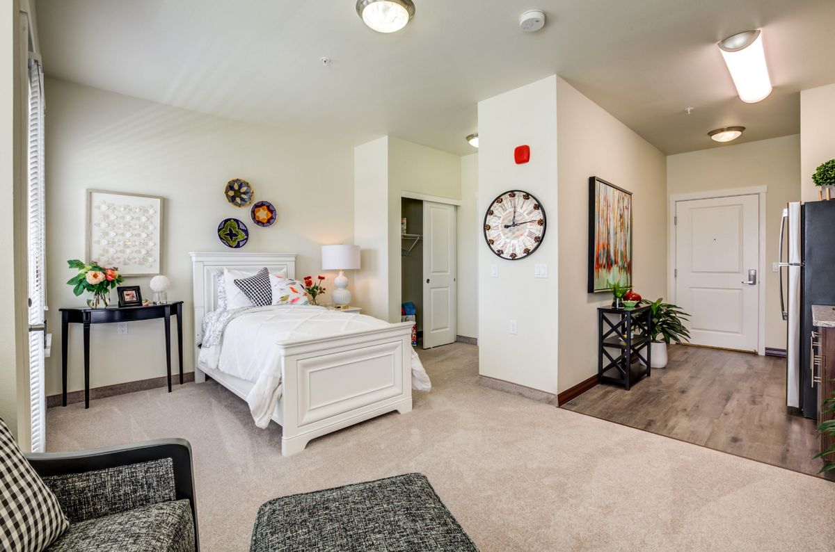 A cozy and elegantly designed bedroom featuring a white bed, decorative wall art, and a large clock.