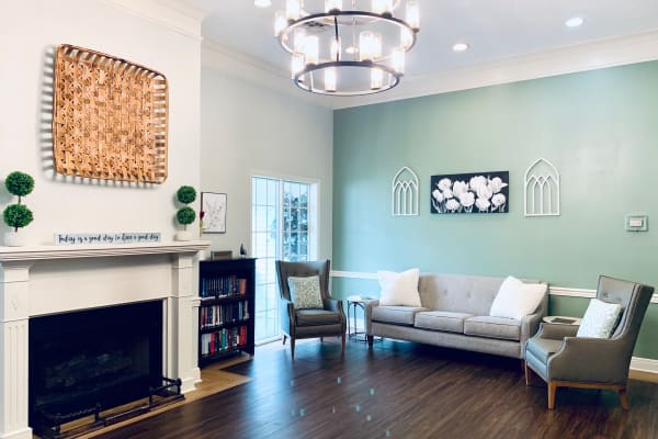 A modern living room with a cozy fireplace, elegant chandelier, and comfortable seating.