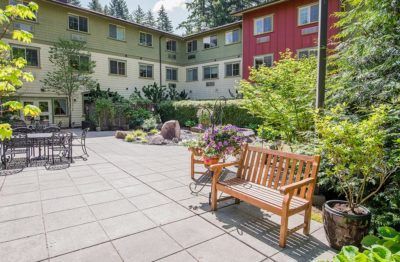 A peaceful courtyard with benches and lush greenery in an apartment complex.
