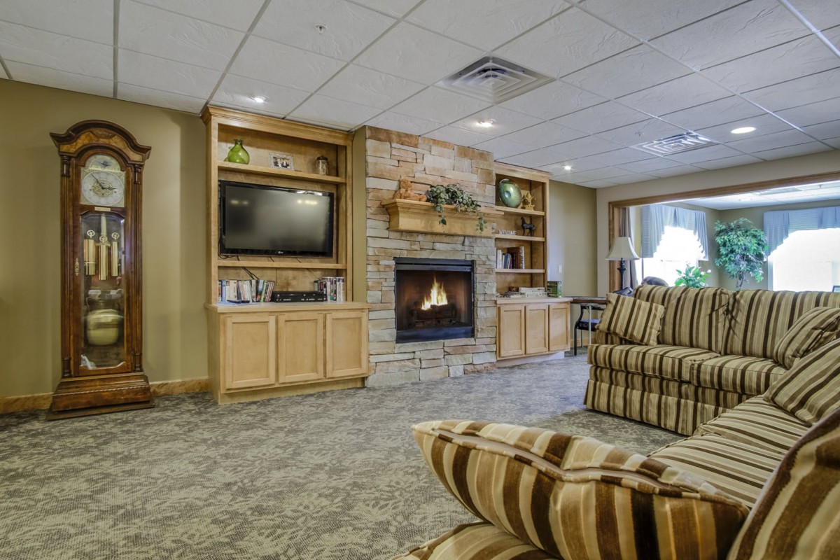 A cozy living room featuring a stone fireplace, built-in shelving with a television, and comfortable seating.