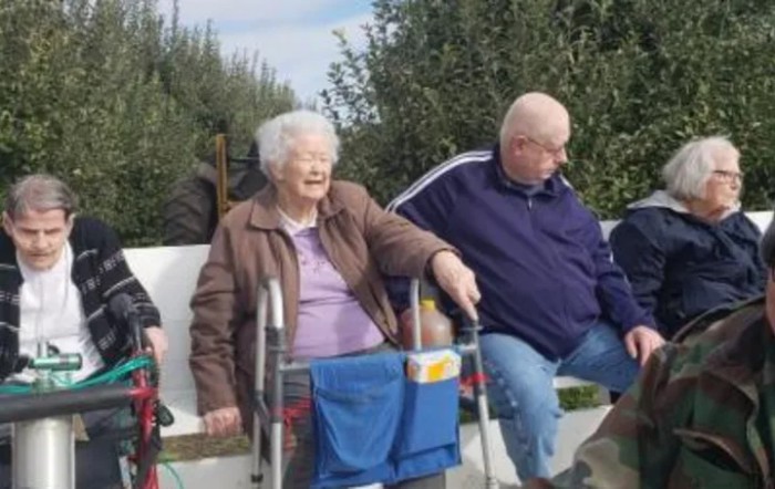 A group of elderly people sitting outdoors, enjoying the company of each other.