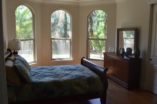 A cozy bedroom with large arched windows allowing abundant natural light in.