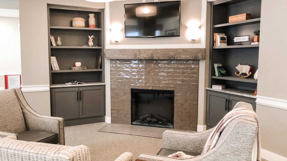 A cozy living room with a fireplace and television, surrounded by built-in shelves.