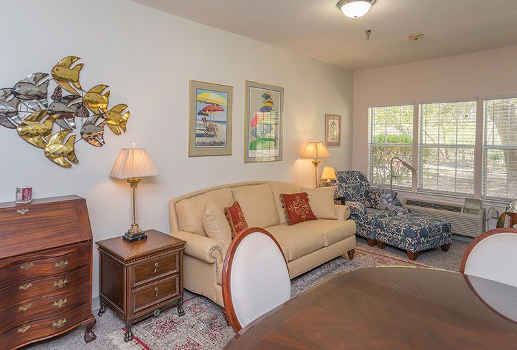 A cozy living room featuring a sofa, armchair, and decorative artwork on the walls.