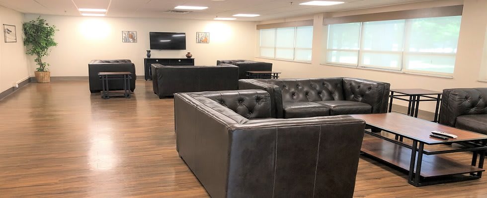 A modern office lounge with leather sofas and a television.