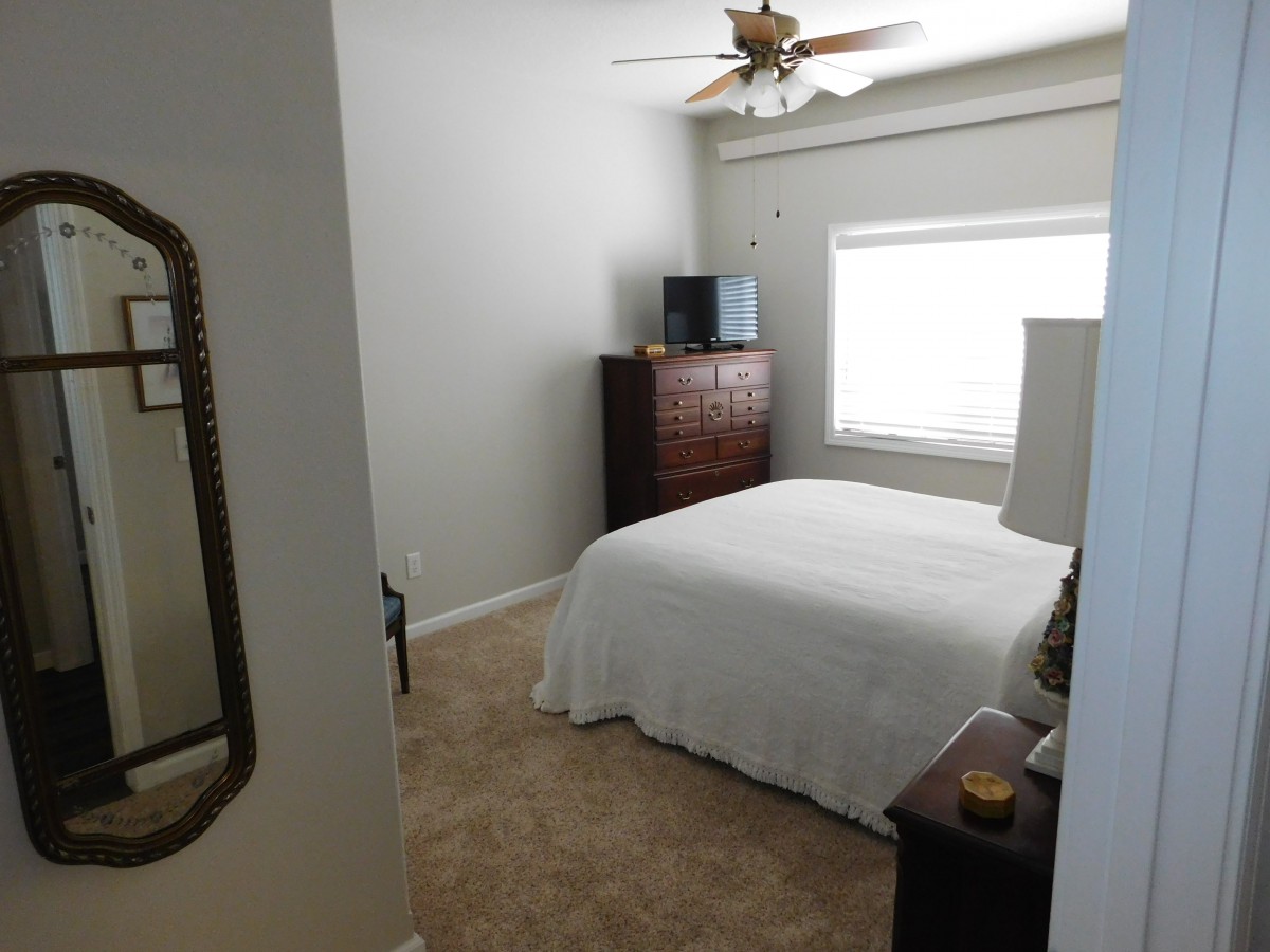 A neatly arranged bedroom with a bed, dresser, and window.