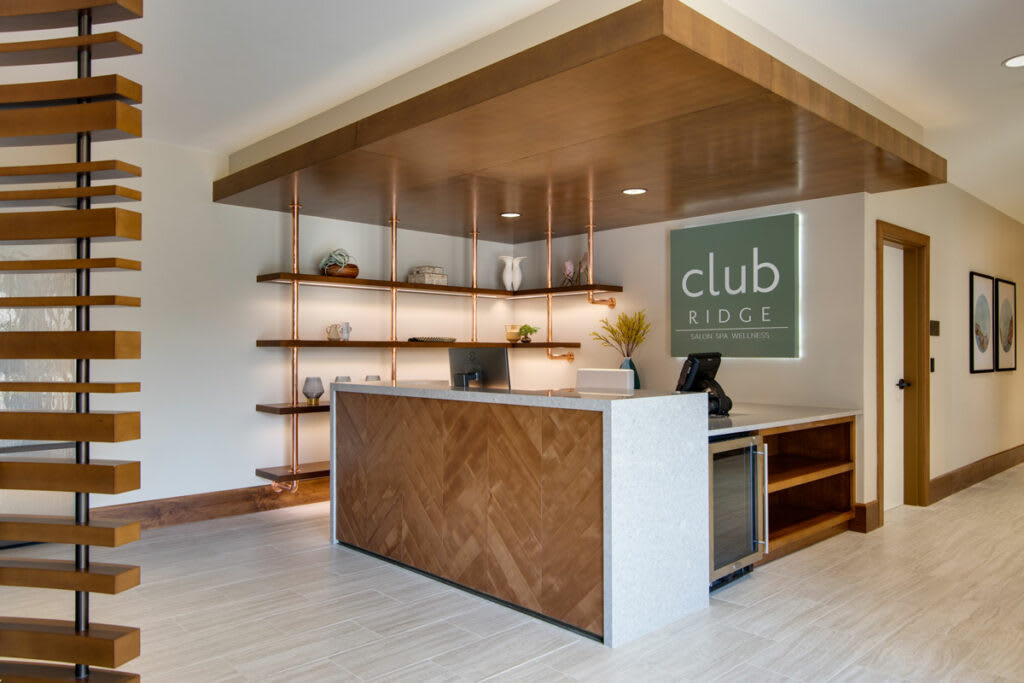 A modern office reception area with a wooden front desk and decorative shelving.