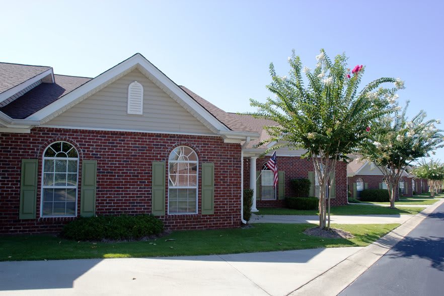 A single-story brick house with a front yard and a tree.