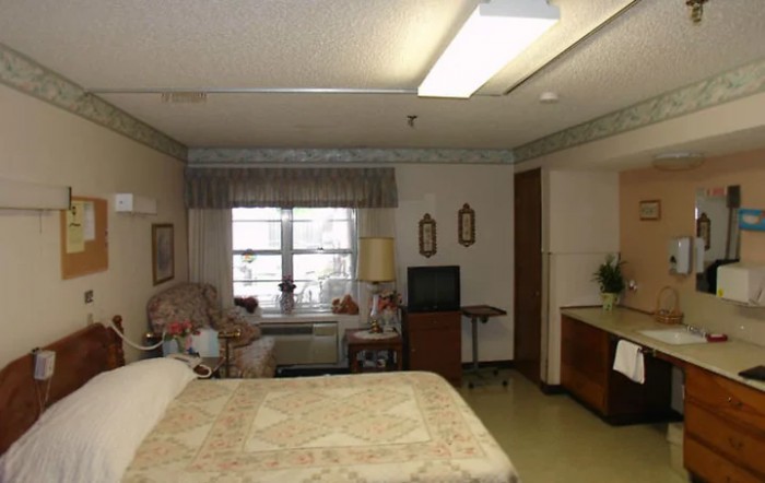 A hospital room with a bed, television, and window with curtains.