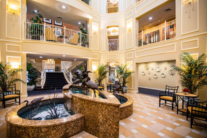 A luxurious lobby featuring a central fountain, balconies, and elegant decor.