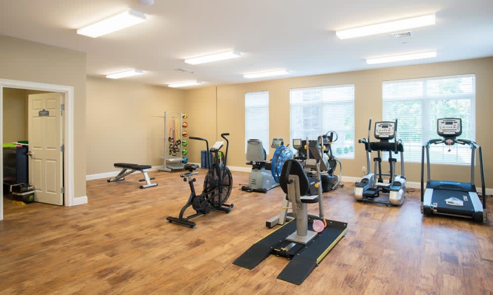 A well-equipped gym with various exercise machines and equipment in a spacious, brightly lit room.