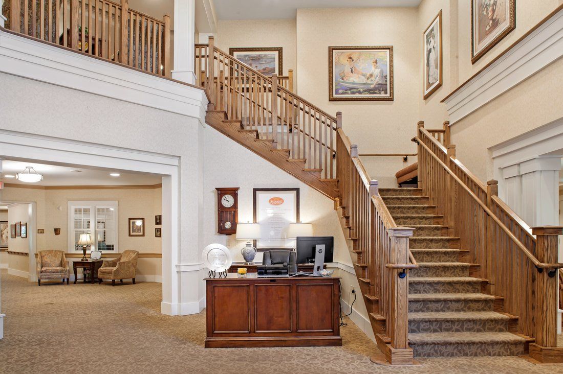 A warmly decorated interior featuring a wooden staircase, artwork on the walls, and a reception desk.