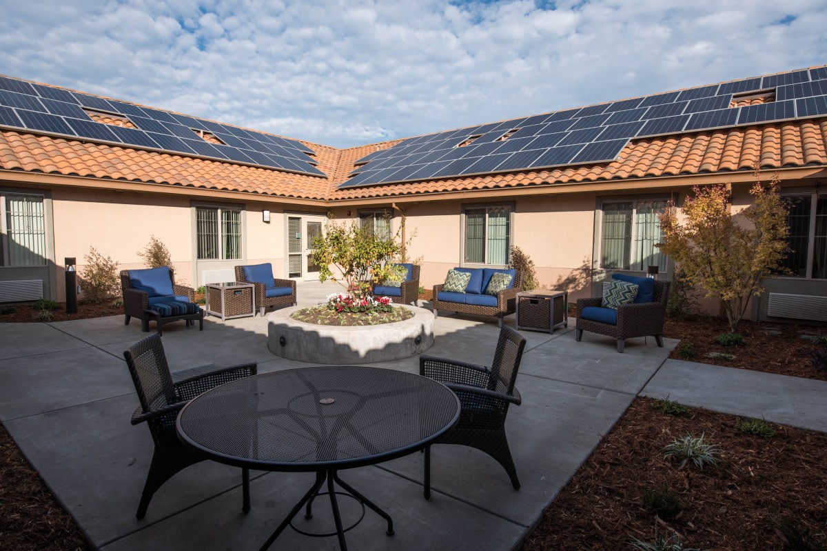 A cozy courtyard with outdoor furniture and surrounding roofs adorned with solar panels.
