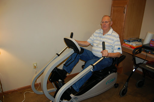 An elderly man using a specialized fitness machine for exercise.