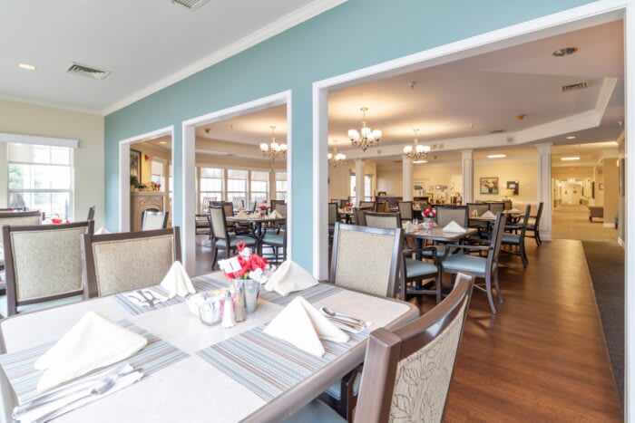 A spacious dining room with neatly arranged tables and chairs, featuring elegant place settings.