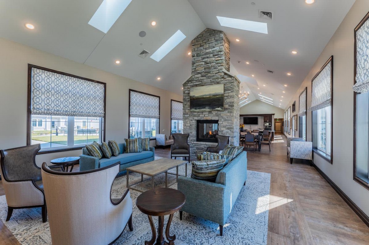 A spacious modern living room with a central stone fireplace and skylights.