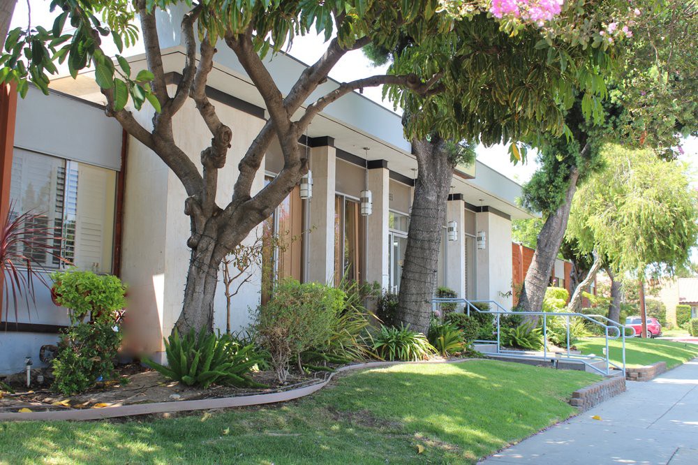 A residential house with a well-maintained garden and trees.