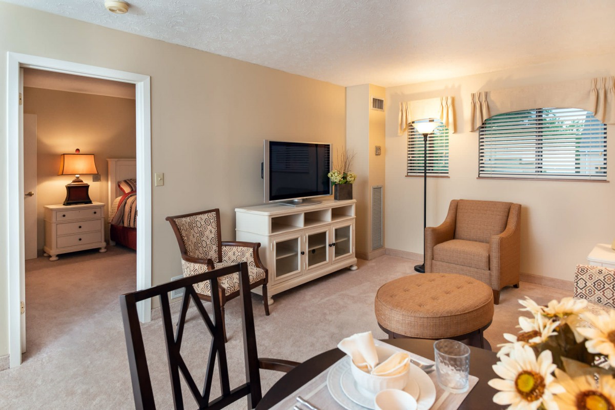 A cozy living room with comfortable seating, a TV, and a dining area.