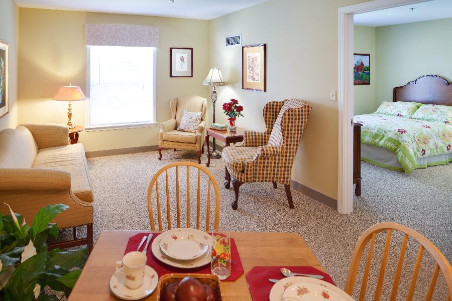 A cozy living and dining area with comfortable armchairs and a set dining table in a brightly lit room.
