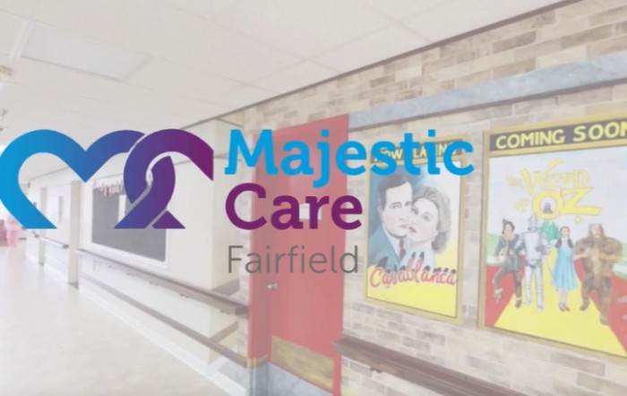 Logo of Majestic Care Fairfield displayed over an image of a corridor with vintage posters.