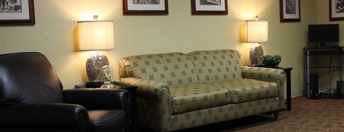 A cozy living room with a patterned sofa, lamps, and framed pictures on the wall.