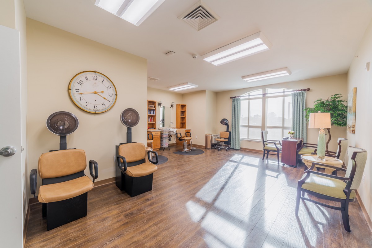A well-lit salon interior with hairdryers, seating areas, and large windows.