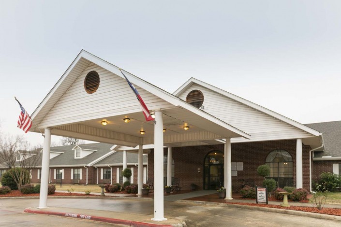 A building with a large entrance and an awning, featuring a flag.