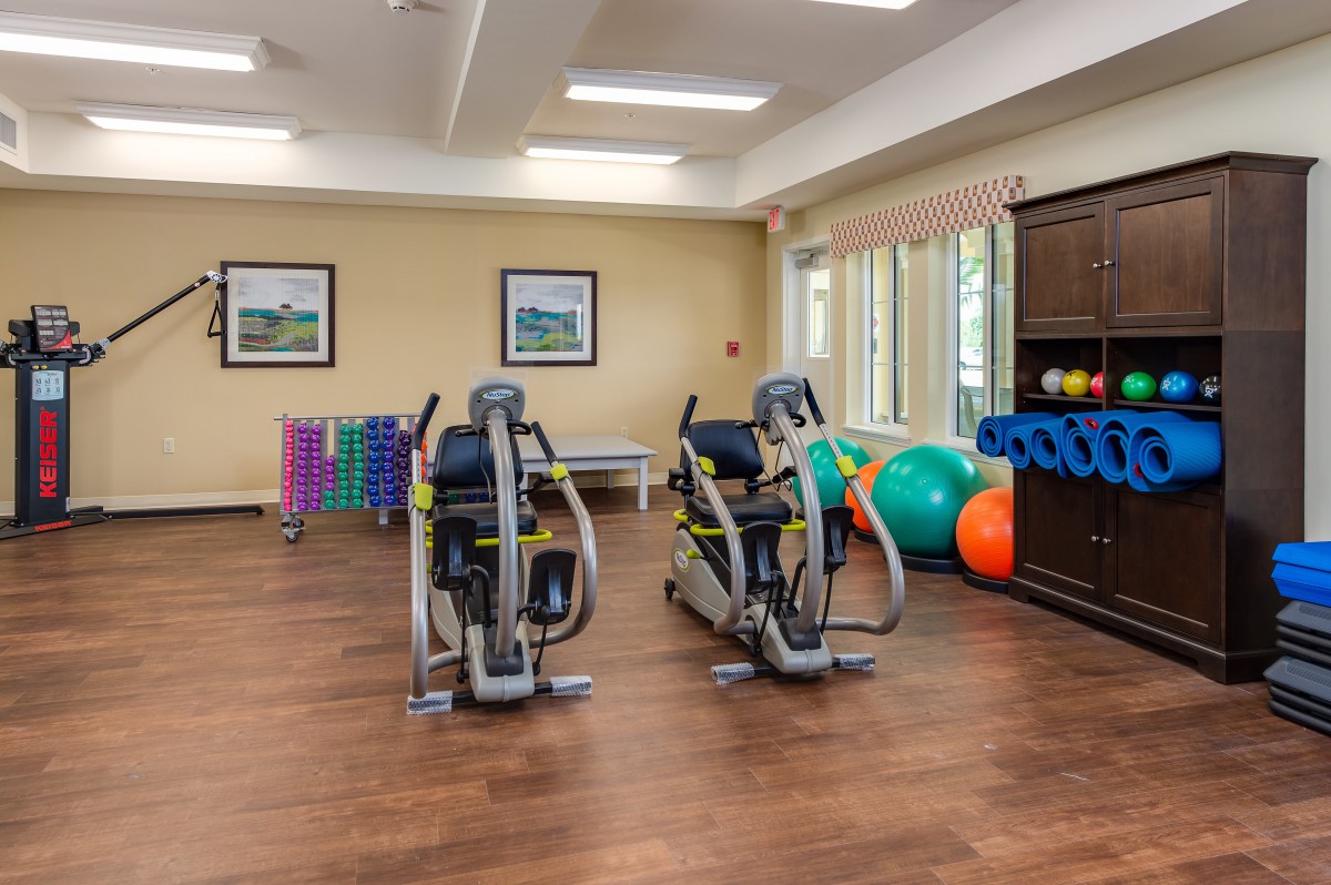 A well-equipped gym room featuring stationary bikes, exercise balls, and dumbbells.