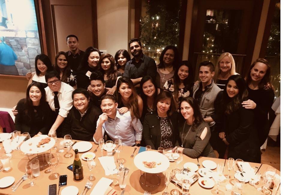 A large group of people gathered around a dinner table, celebrating together in a restaurant setting.