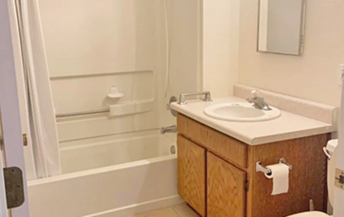 A simple bathroom featuring a sink, bathtub, and cabinet.