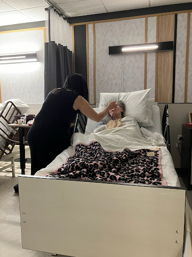 A caregiver attending to a patient in a hospital room.