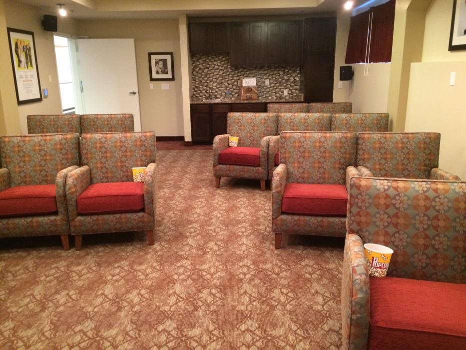 An empty screening room with comfortable seating and popcorn in each seat.