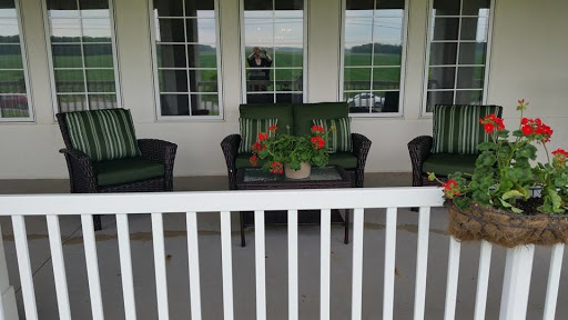 A cozy porch setup with green seating and vibrant plants, perfect for relaxation.