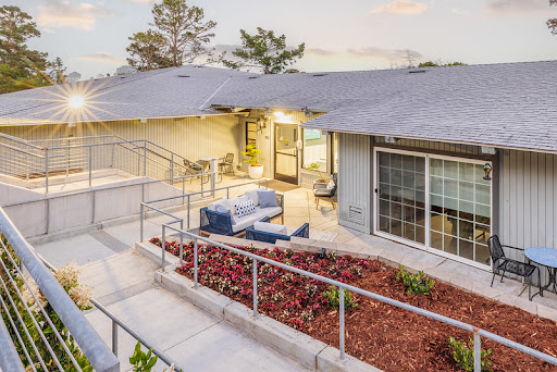A beautifully designed modern house with inviting outdoor seating, showcasing elegant landscaping under soft evening light.