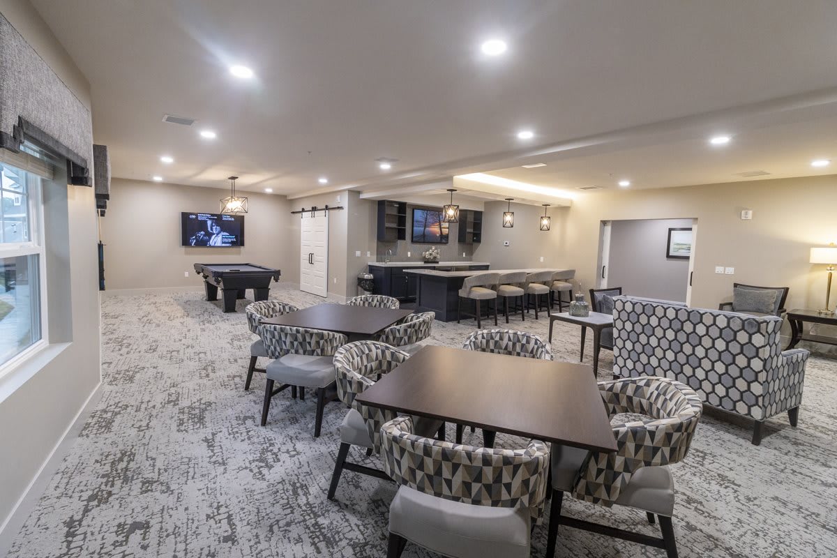 A modern recreation room featuring a bar area, pool table, and comfortable seating.