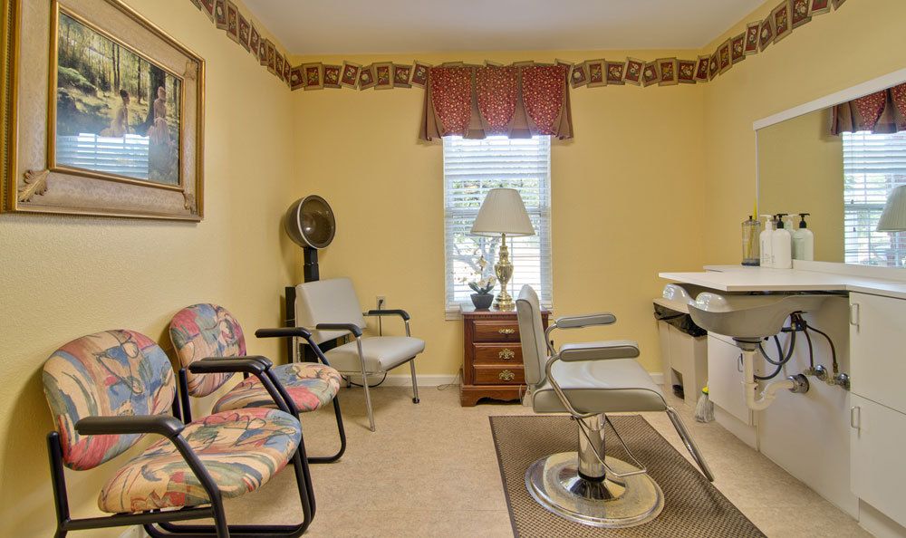 A cozy waiting room with chairs, a fan, and a table by the window.