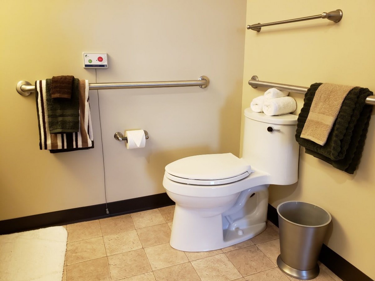 A clean and organized bathroom with a toilet, towel rack, and grab bar.